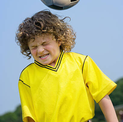 young child hitting soccer ball with head