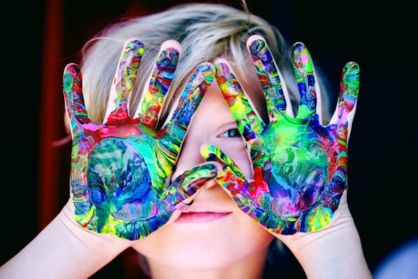 young child holding up hands with paint on them
