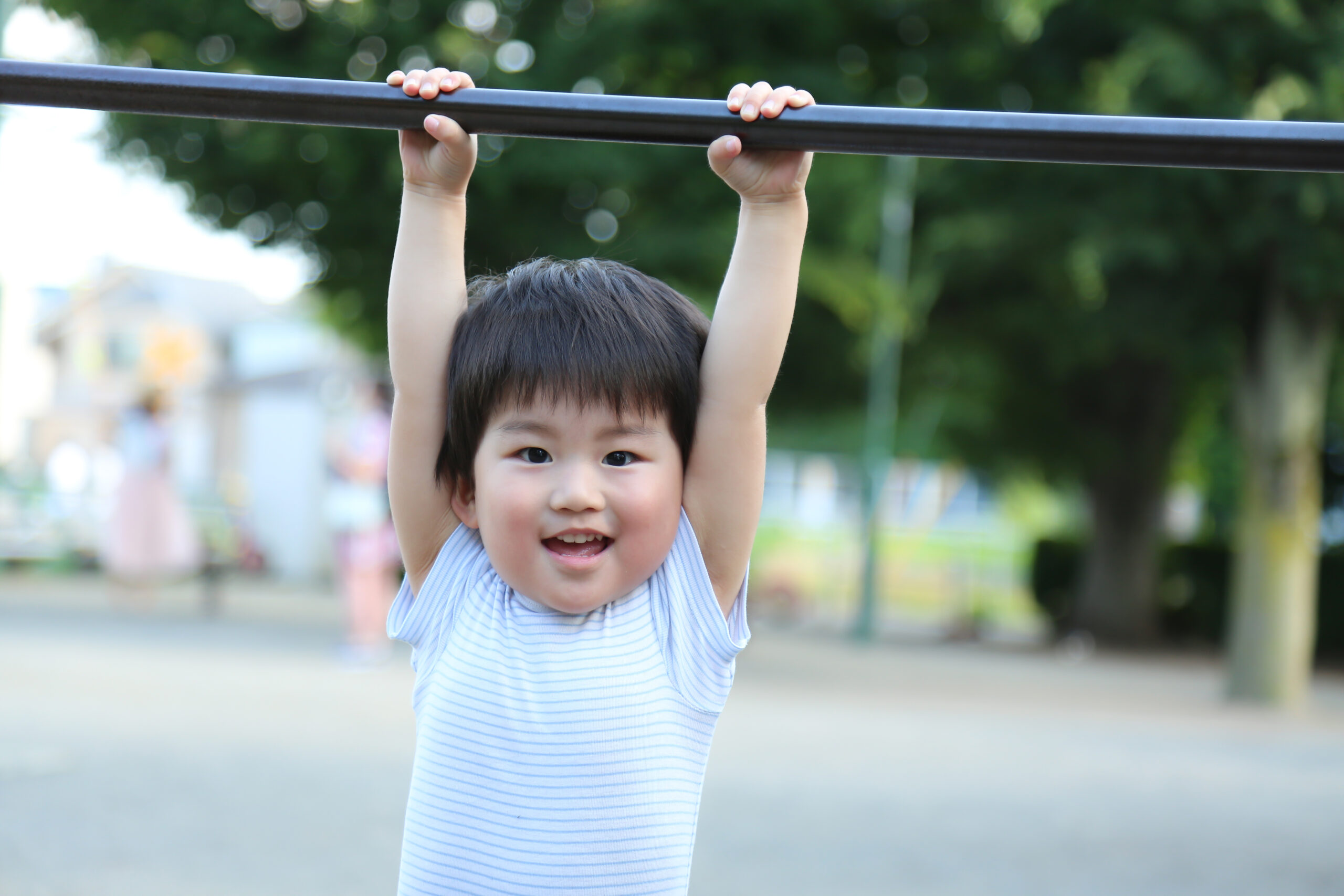 Preschool-aged child hanging from monkey bars